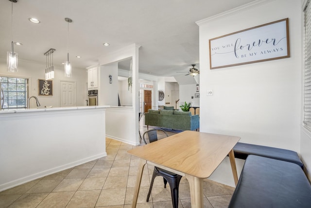 tiled dining area featuring ceiling fan, crown molding, and sink