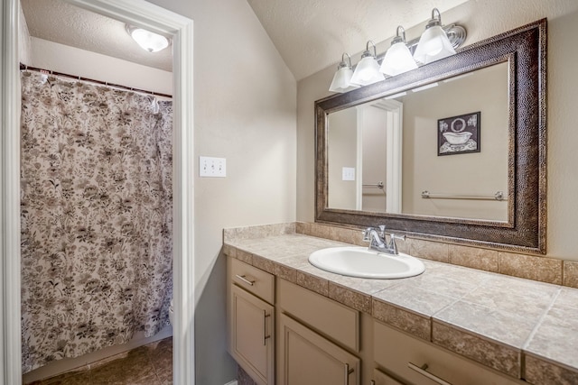 bathroom featuring tile patterned floors, vanity, lofted ceiling, and a textured ceiling