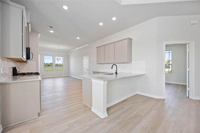 kitchen with stove, kitchen peninsula, a wealth of natural light, and light hardwood / wood-style flooring