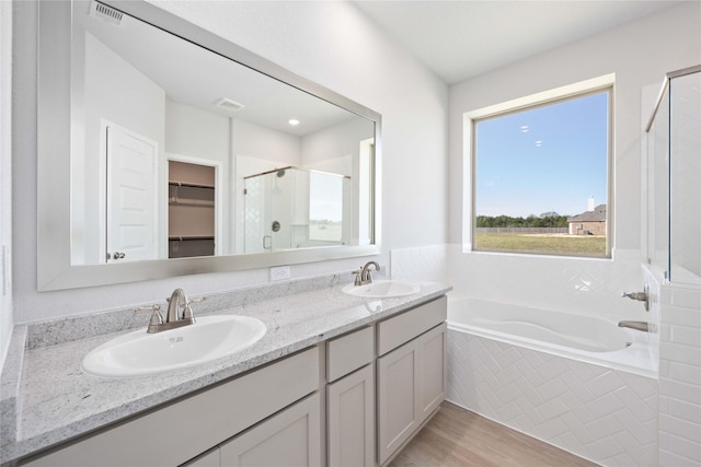 bathroom with hardwood / wood-style floors, vanity, and shower with separate bathtub