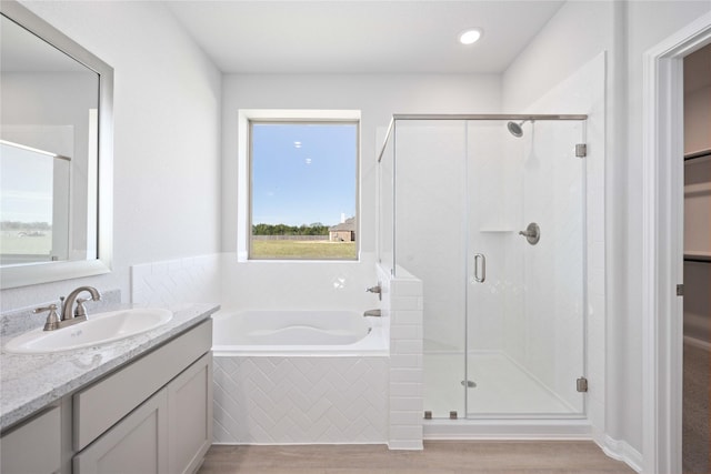 bathroom featuring hardwood / wood-style flooring, vanity, and plus walk in shower