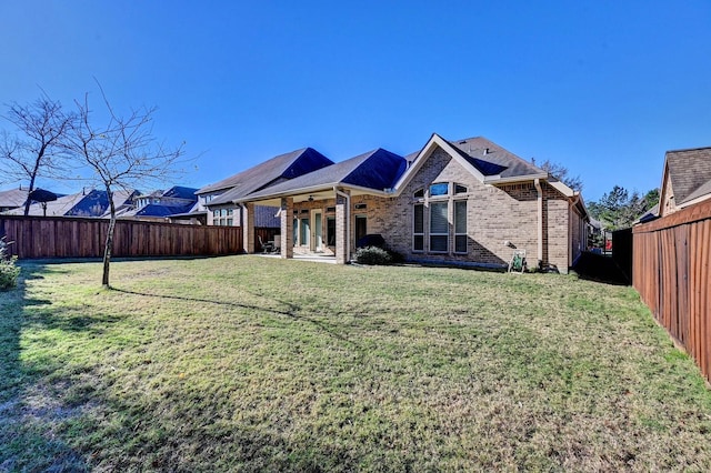 back of property with ceiling fan and a yard