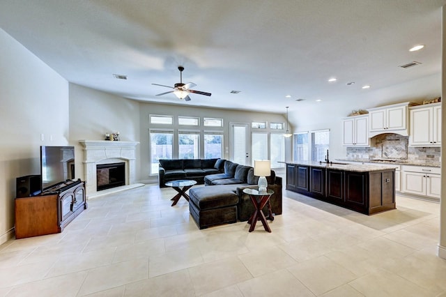 living room featuring ceiling fan, sink, and light tile patterned flooring