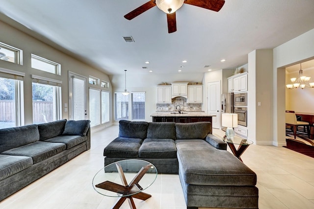 living room with a wealth of natural light, sink, light tile patterned flooring, and ceiling fan with notable chandelier