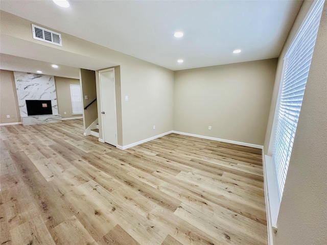 unfurnished living room with light wood-type flooring and a high end fireplace