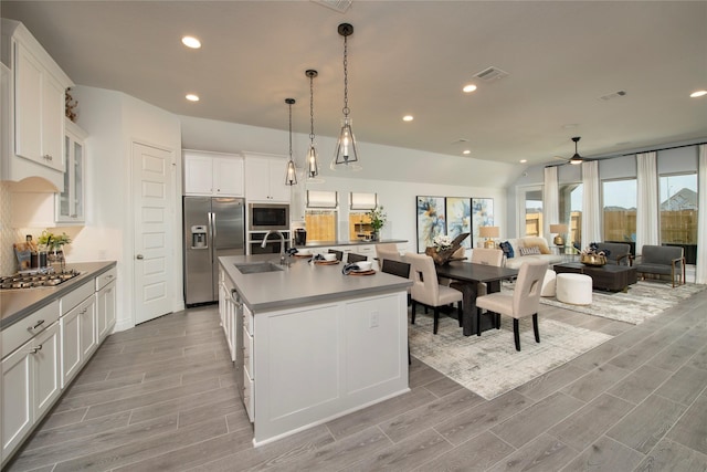 kitchen with pendant lighting, a kitchen island with sink, sink, appliances with stainless steel finishes, and white cabinetry