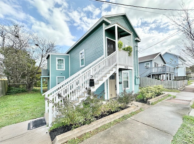 view of front of property with stairs, a front yard, and fence