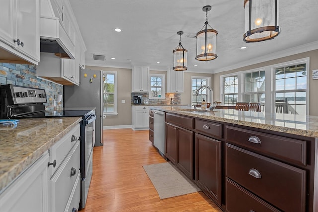 kitchen with white cabinets, decorative light fixtures, sink, and appliances with stainless steel finishes