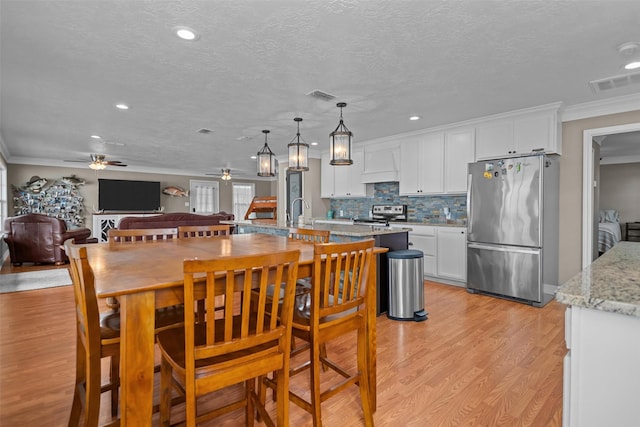 kitchen with appliances with stainless steel finishes, light stone counters, ceiling fan, white cabinetry, and hanging light fixtures