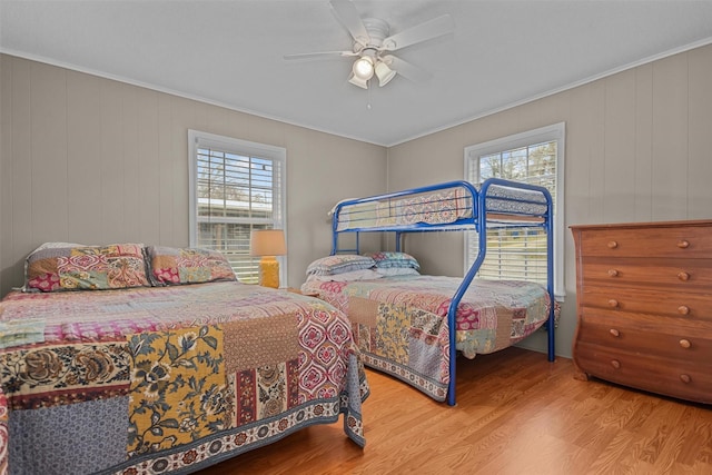 bedroom with hardwood / wood-style floors, ceiling fan, crown molding, and multiple windows