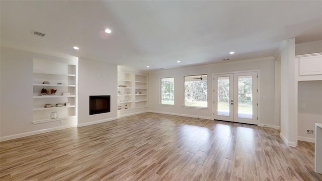 unfurnished living room with built in shelves, light hardwood / wood-style flooring, and french doors