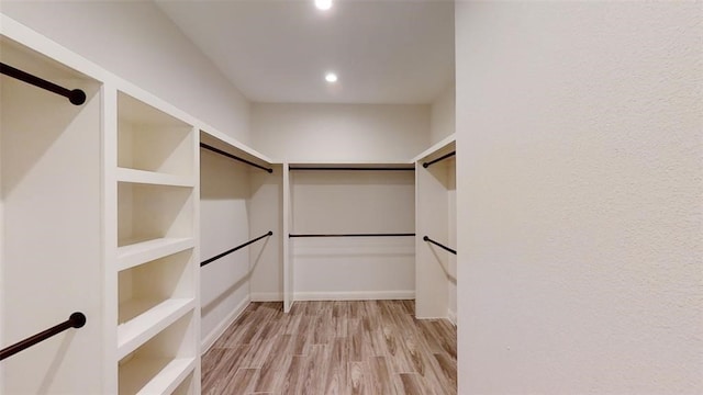 walk in closet with light hardwood / wood-style floors