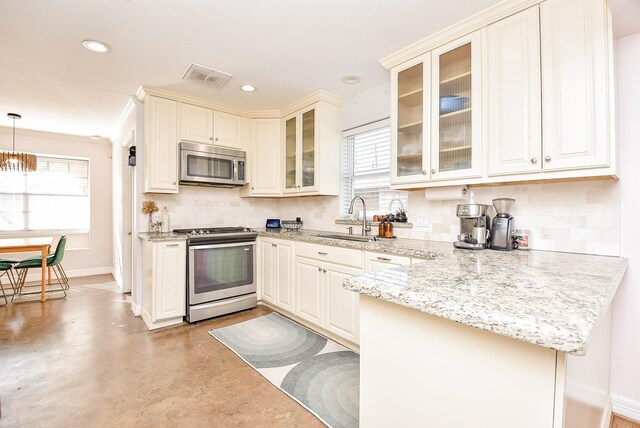 kitchen with kitchen peninsula, light stone counters, stainless steel appliances, sink, and pendant lighting