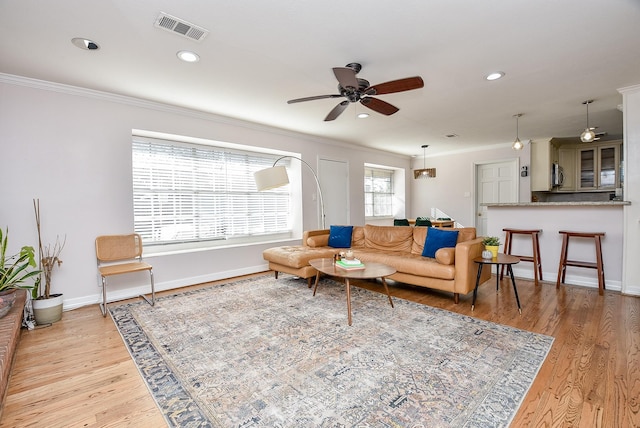 living room with light hardwood / wood-style floors, ceiling fan, and crown molding