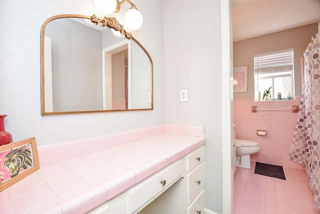 bathroom featuring tile patterned flooring, vanity, tile walls, and toilet