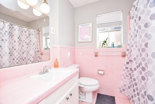 bathroom featuring toilet, vanity, tile patterned floors, and tile walls