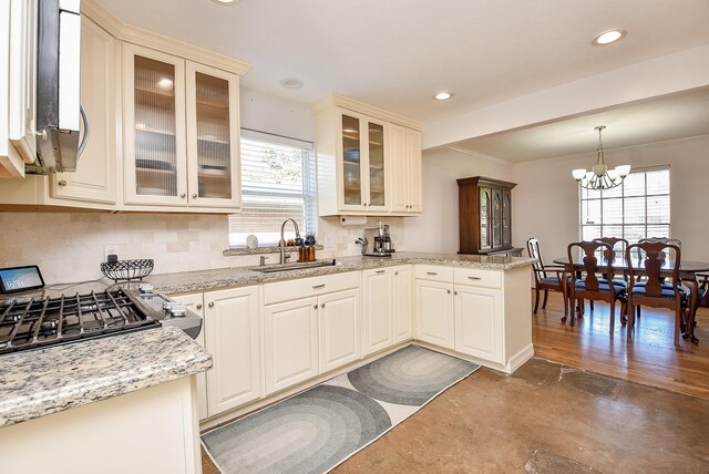 kitchen with sink, light stone counters, plenty of natural light, a chandelier, and pendant lighting