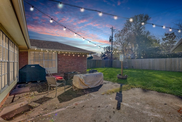 patio terrace at dusk with grilling area and a yard