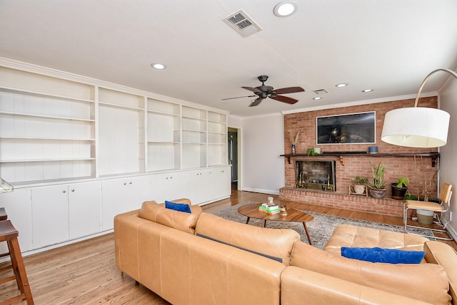 living room featuring light hardwood / wood-style floors, a brick fireplace, ceiling fan, and crown molding