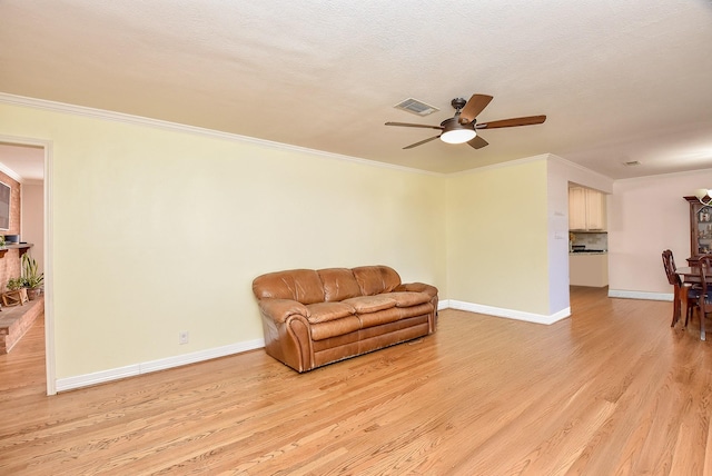 sitting room with a textured ceiling, light hardwood / wood-style floors, ceiling fan, and crown molding