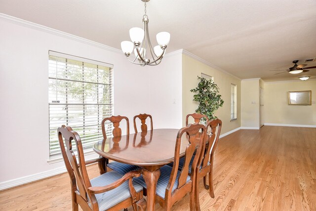 dining room featuring light wood-type flooring, ceiling fan with notable chandelier, and crown molding