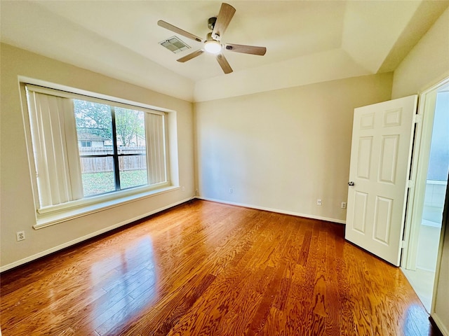 unfurnished room with hardwood / wood-style floors, ceiling fan, and a raised ceiling