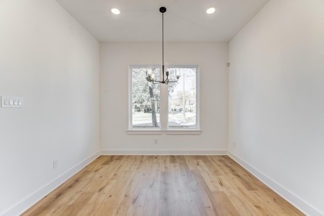 unfurnished dining area with a notable chandelier and light hardwood / wood-style floors