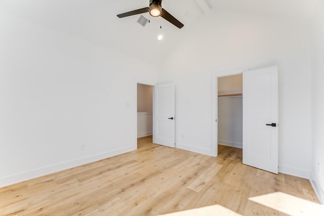 unfurnished bedroom featuring high vaulted ceiling, light hardwood / wood-style flooring, ceiling fan, a spacious closet, and beamed ceiling