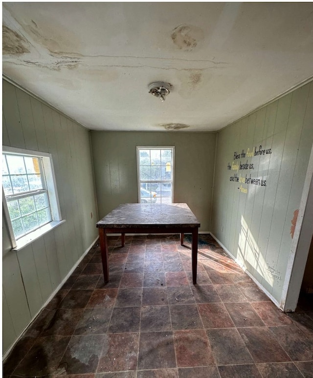 unfurnished dining area featuring wood walls