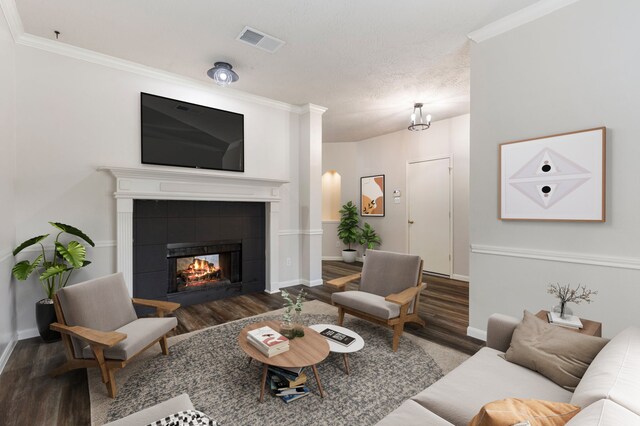 living room with a tile fireplace, crown molding, and hardwood / wood-style floors