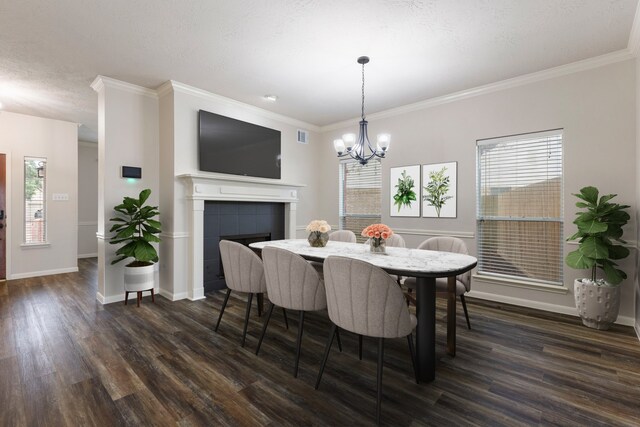 dining area featuring a tiled fireplace, crown molding, a chandelier, and dark hardwood / wood-style floors