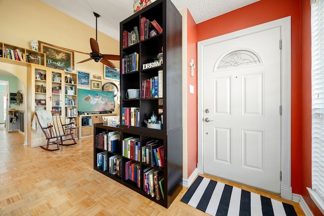 entryway featuring ceiling fan, parquet floors, a textured ceiling, and lofted ceiling