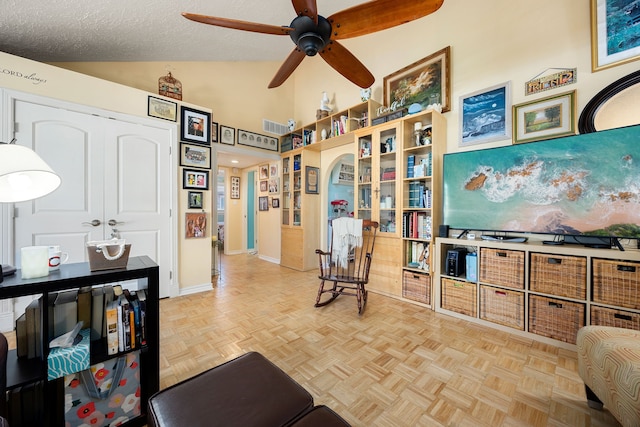 living area featuring a textured ceiling, light parquet floors, ceiling fan, and vaulted ceiling