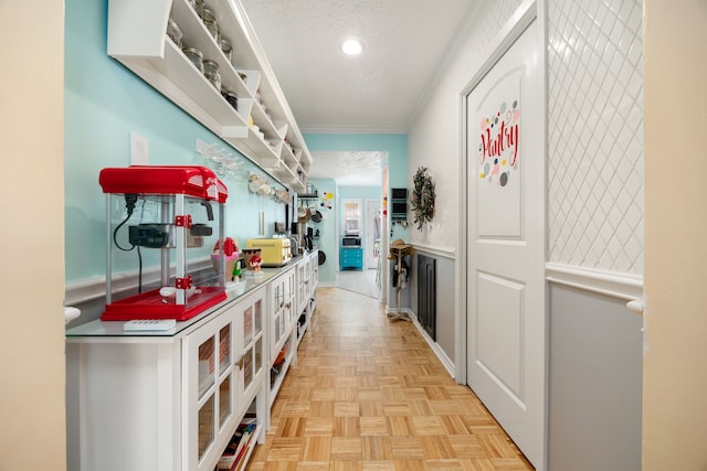 hallway featuring light parquet flooring, a textured ceiling, and ornamental molding