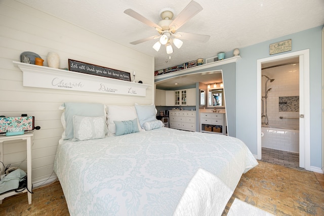 bedroom featuring a textured ceiling, connected bathroom, and ceiling fan