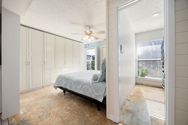 bedroom featuring ceiling fan, a closet, a textured ceiling, and multiple windows