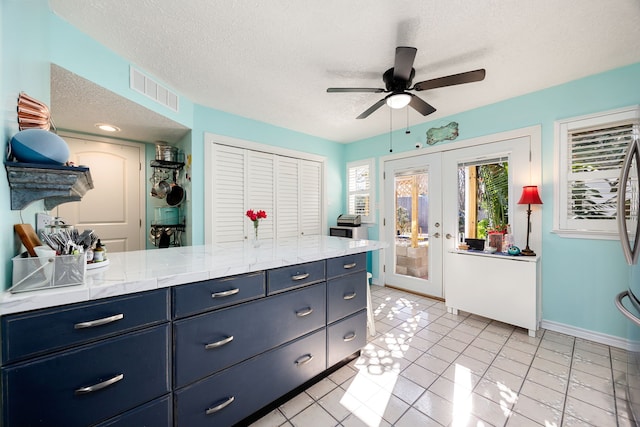 kitchen featuring french doors, light tile patterned floors, a textured ceiling, and blue cabinets