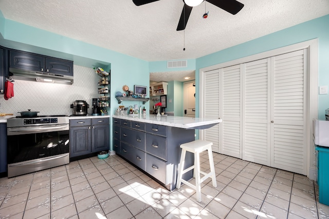 kitchen with ceiling fan, stainless steel range, tasteful backsplash, kitchen peninsula, and a breakfast bar