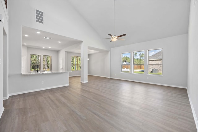 unfurnished living room featuring ceiling fan, sink, high vaulted ceiling, and hardwood / wood-style flooring