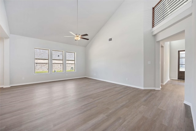 unfurnished living room with ceiling fan, high vaulted ceiling, and hardwood / wood-style flooring