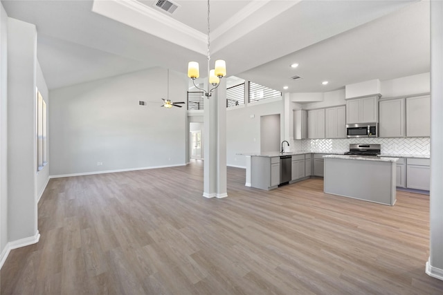 kitchen with appliances with stainless steel finishes, backsplash, gray cabinetry, ceiling fan with notable chandelier, and decorative light fixtures