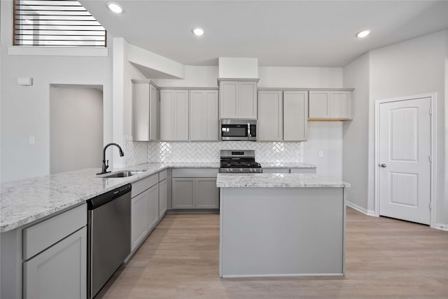 kitchen with gray cabinets, light stone counters, sink, and stainless steel appliances