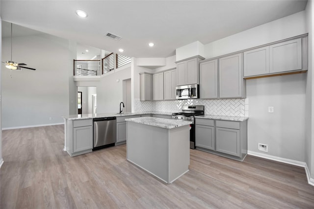 kitchen featuring ceiling fan, stainless steel appliances, light stone counters, kitchen peninsula, and gray cabinets