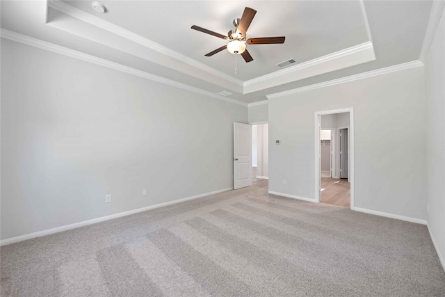 carpeted spare room with a tray ceiling, crown molding, and ceiling fan