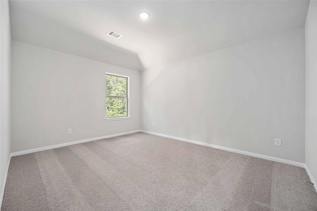 carpeted spare room featuring vaulted ceiling