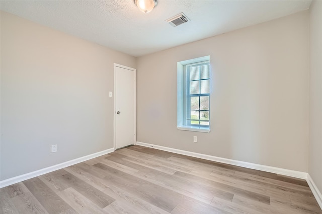 unfurnished room featuring a textured ceiling and light wood-type flooring