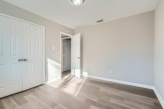 unfurnished bedroom featuring light hardwood / wood-style flooring and a closet