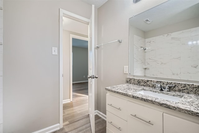 bathroom with tiled shower, vanity, and hardwood / wood-style flooring