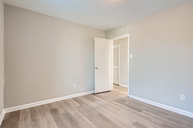 spare room with light hardwood / wood-style floors and a textured ceiling