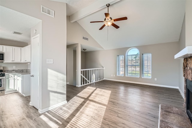 unfurnished living room featuring beam ceiling, ceiling fan, hardwood / wood-style floors, and high vaulted ceiling